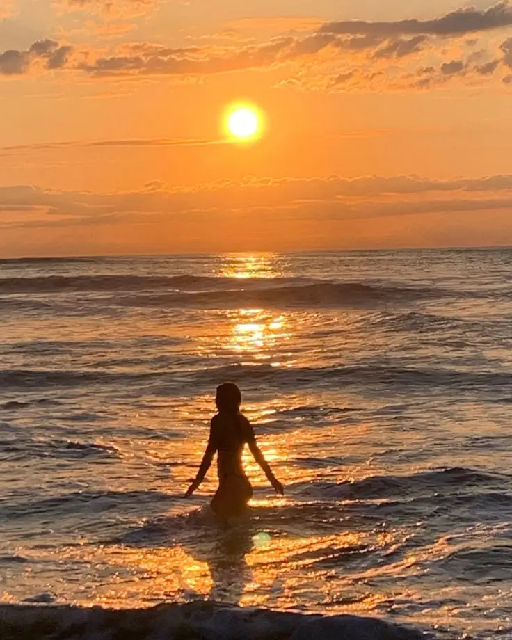 🧡 Person enjoys the ocean at sunset, bathed in orange glow and peaceful waves. | Sky Rye Design Person enjoys the ocean at sunset, bathed in orange glow and peaceful waves.
