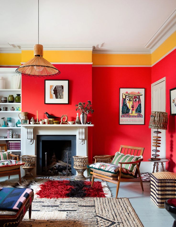 Vibrant living room with red walls, colorful art, cozy fireplace, patterned rugs, and stylish retro furniture.