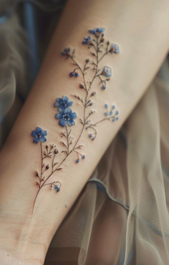 Close-up of a delicate blue floral tattoo on forearm, showcasing intricate details and subtle hues for artistic inspiration.