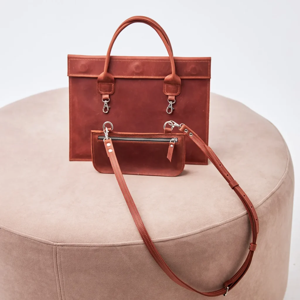 Brown leather handbag with detachable pouch on display.