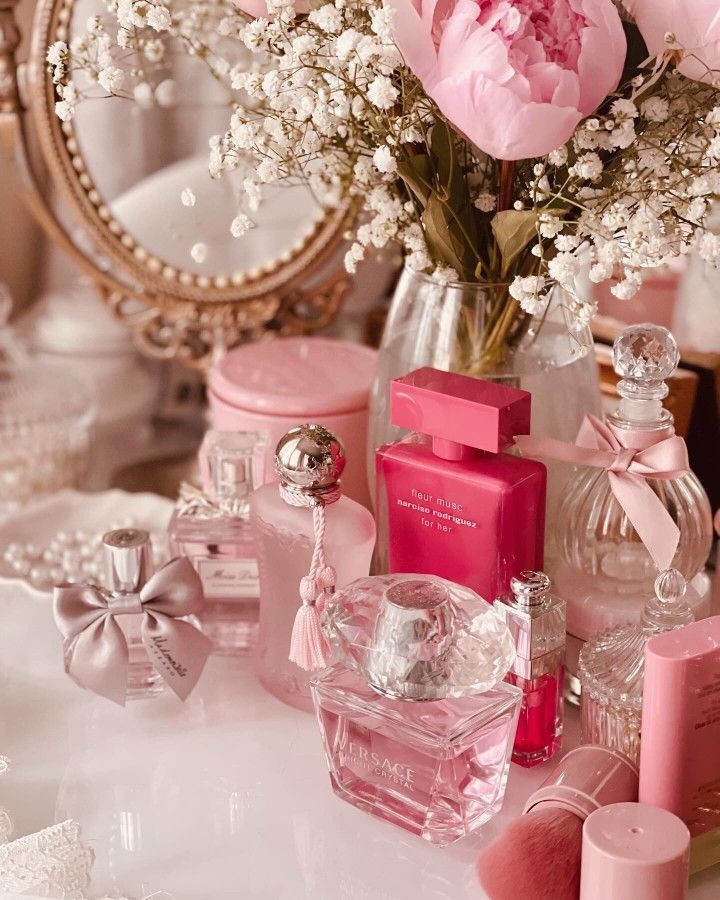 Elegant vanity setup with pink perfume bottles, flowers, and a vintage mirror, creating a luxurious feminine ambiance.