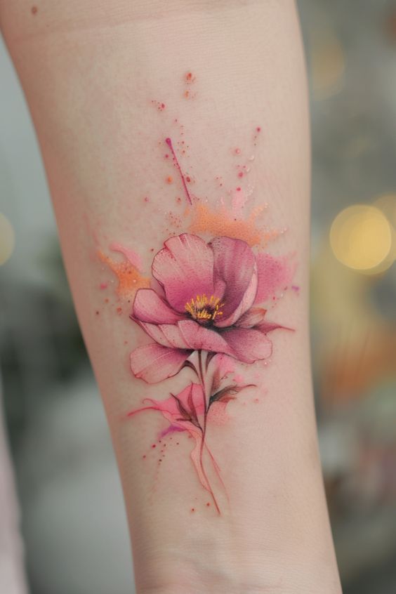 Watercolor pink flower tattoo on forearm, featuring vibrant splashes and delicate petals. Perfect for floral tattoo inspiration.