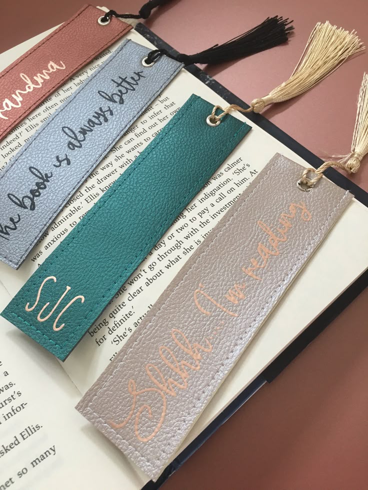 Colorful leather bookmarks with tassels and text on an open book for stylish reading accessories.