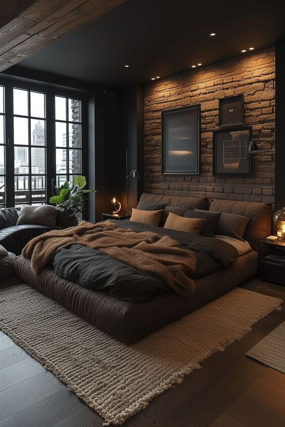 Modern loft bedroom with textured brick wall, cozy bedding, and ambient lighting. Large window with city view.