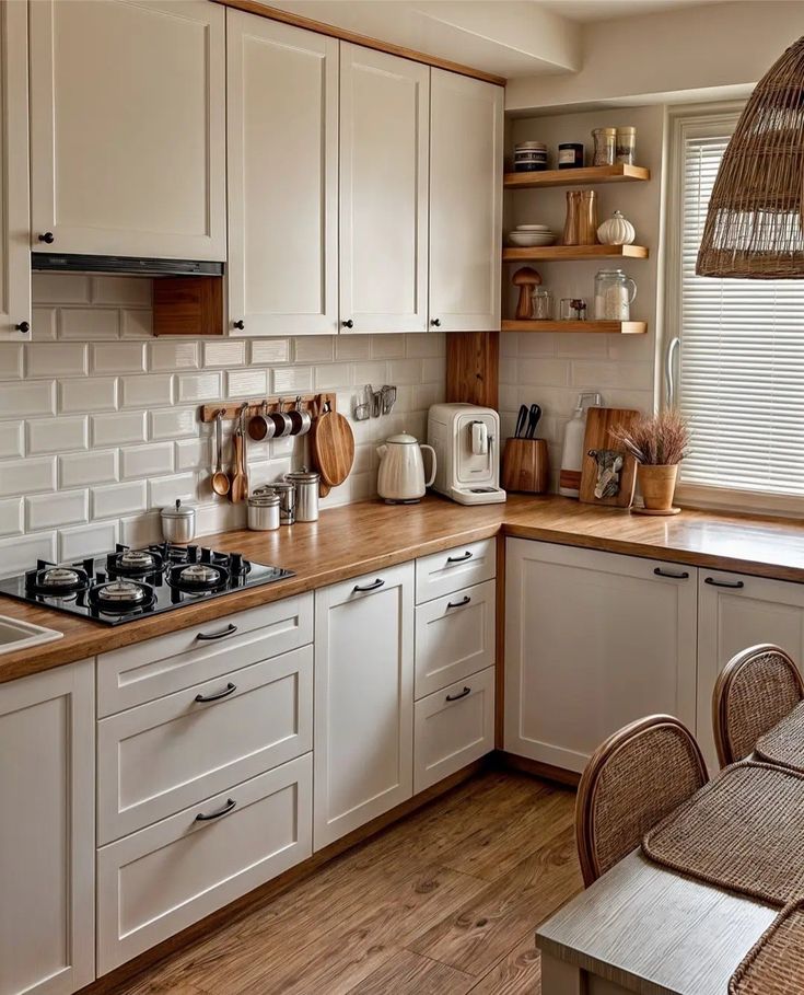 Cozy kitchen with white cabinets, wooden countertops, open shelves, and natural light from large window blinds.