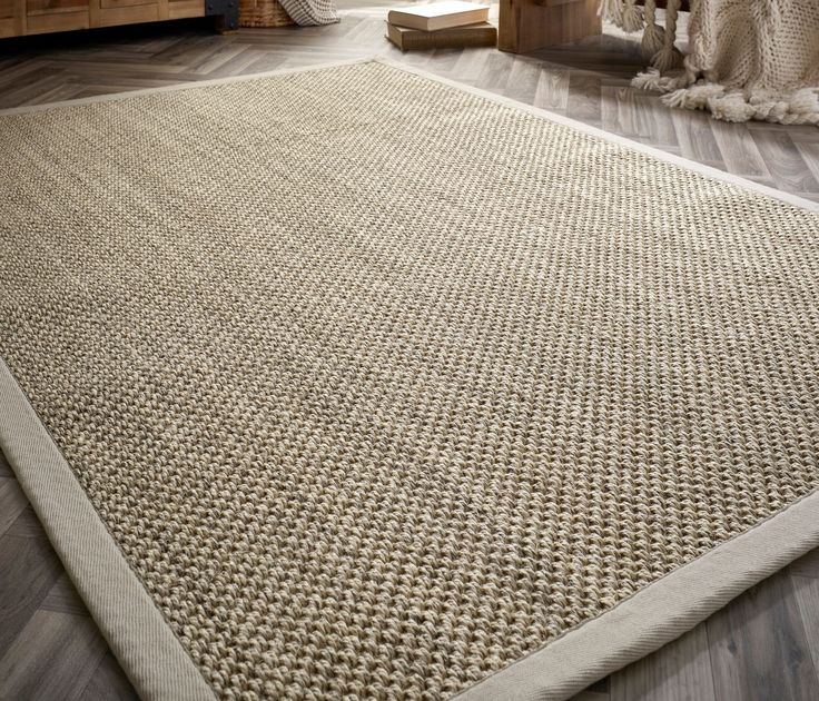 Beige jute rug on wooden floor in cozy living room setting.