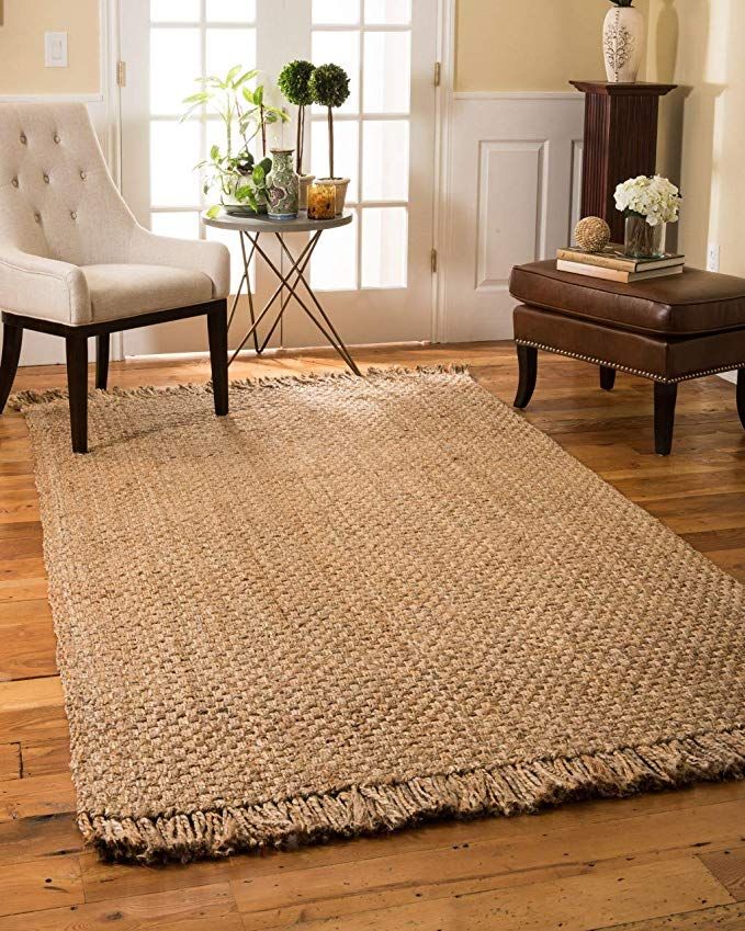 Cozy room with a woven jute rug, elegant chair, side table, and potted plants on wooden flooring.