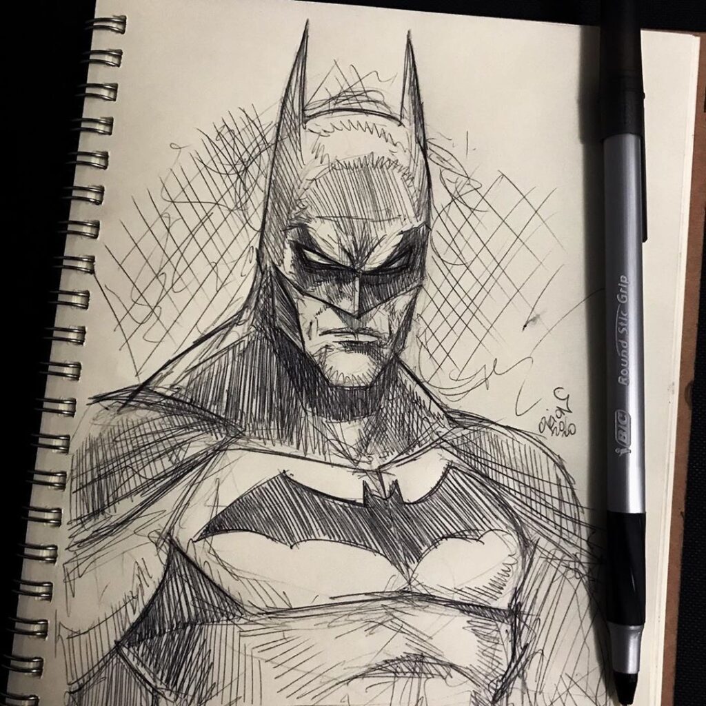 Sketch of superhero in mask and cape on notepad, ink pen lying nearby, detailed crosshatch shading.