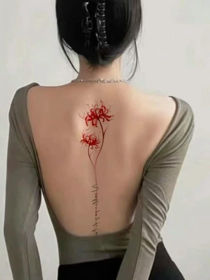 Woman with a tattoo of red flowers on her back, wearing a backless top.