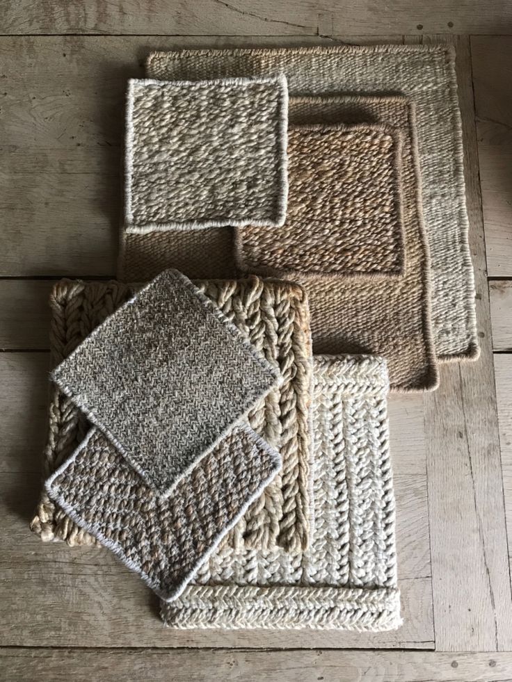 Woven fabric swatches in earthy tones displayed on a wooden surface, showcasing texture and pattern variety.