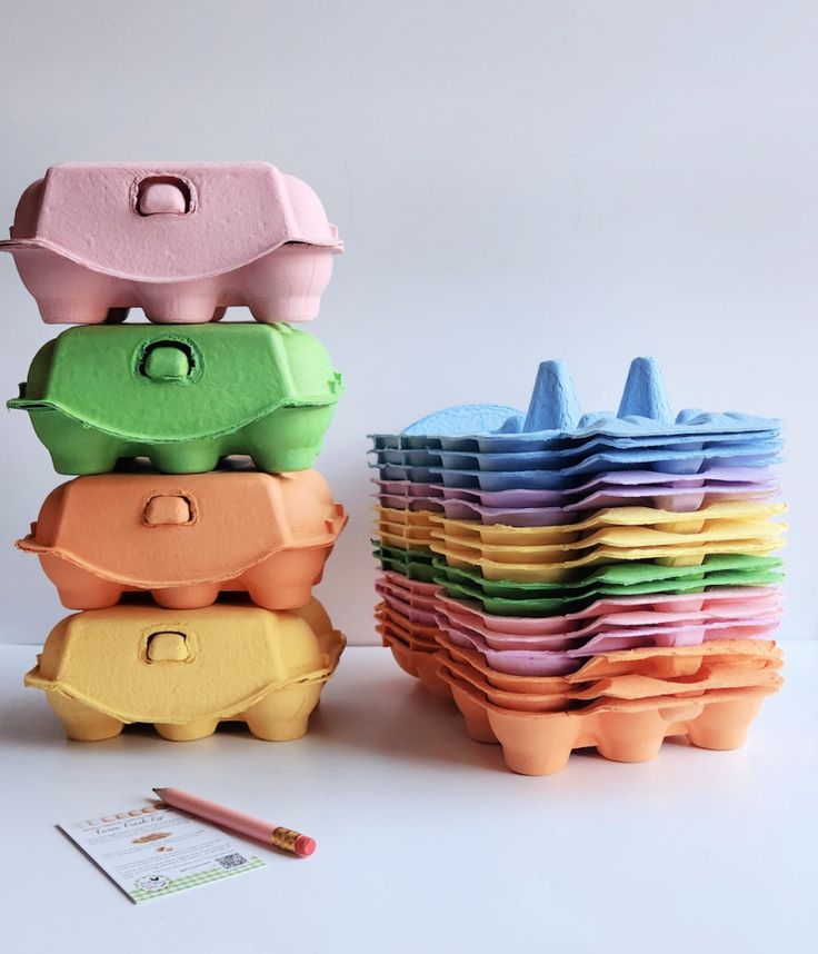 Colorful stacked egg cartons and a notepad with pencil on a white background.