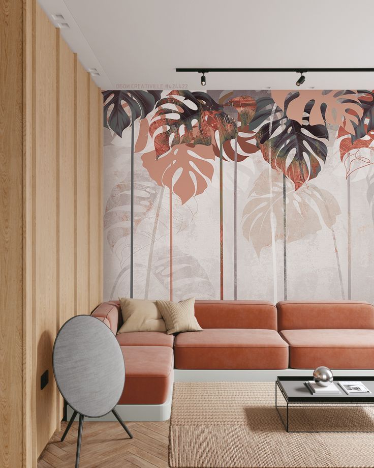 Modern living room with tropical leaf mural, orange sectional sofa, wood paneling, and minimalist coffee table.