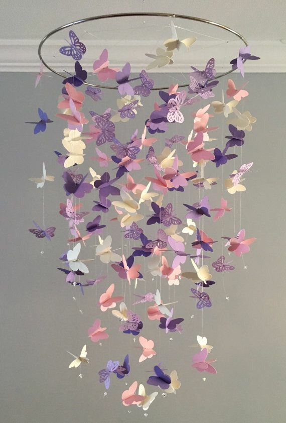 Hanging butterfly mobile with pastel-colored paper butterflies for nursery decoration against a neutral background.