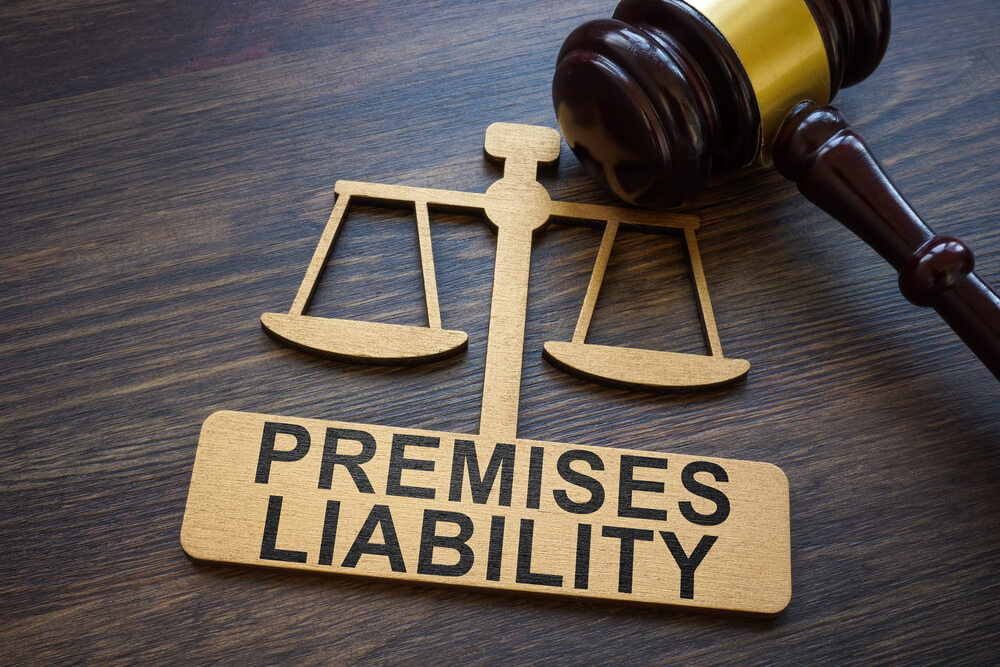 Scales and gavel on a table with Premises Liability sign, symbolizing legal responsibility for property safety.