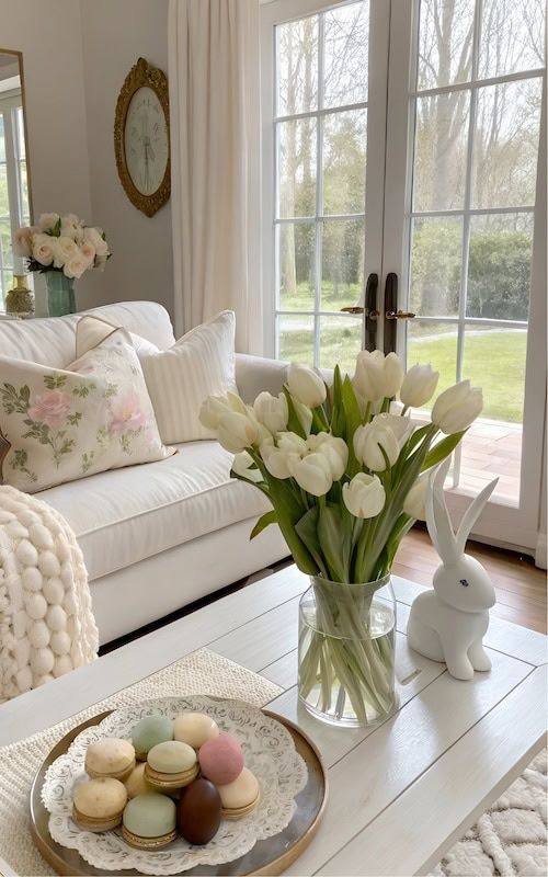 Elegant living room with white tulips, macarons, and cozy decor by a sunlit window, perfect for spring inspiration.