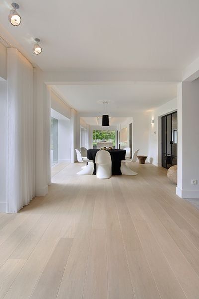 Spacious modern dining room with light wood flooring, white chairs, and large windows for natural light.