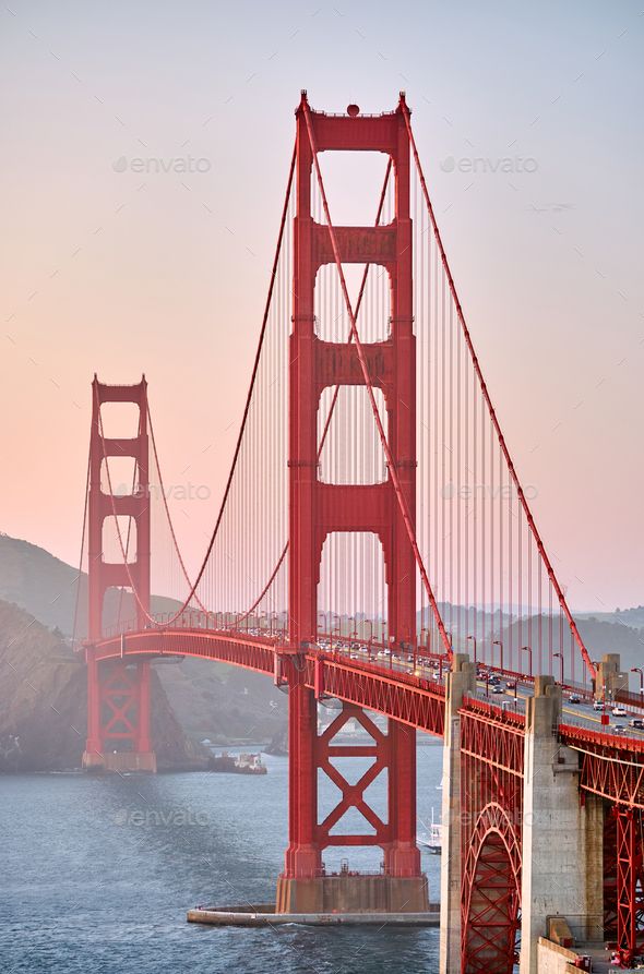 Golden Gate Bridge at sunset with cars crossing over the water, iconic landmark in San Francisco, California.