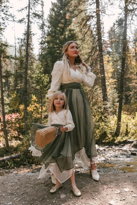 Mother and daughter in matching dresses, enjoying a serene forest walk with natural light filtering through the trees.