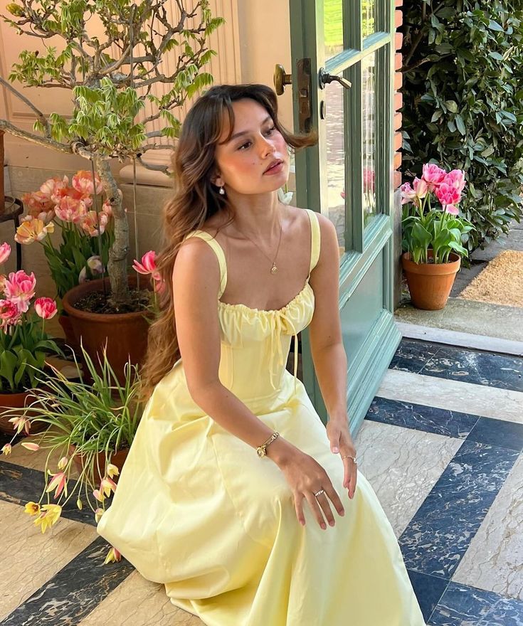 In a love affair with pastel shades 💐 JASMINE Woman in a yellow dress kneeling near tulips, surrounded by plants in a sunlit room with open door. | Sky Rye Design Woman in a yellow dress kneeling near tulips, surrounded by plants in a sunlit room with open door.