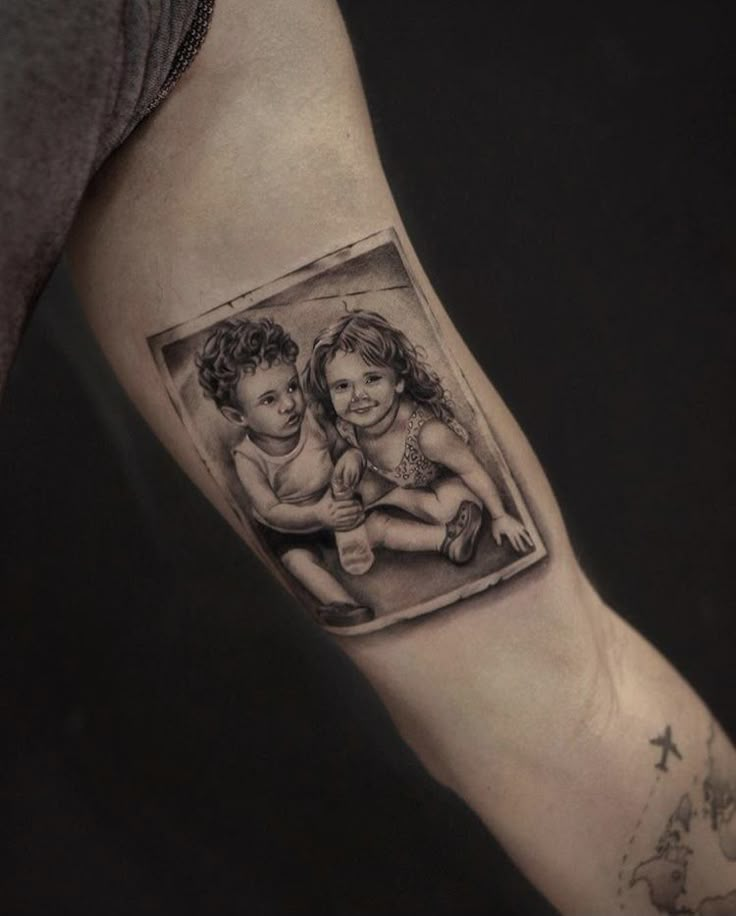 Tattoo of two smiling children sitting together, inked on a person's inner arm.