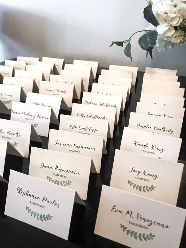 Wedding place cards with names and table assignments elegantly arranged on a table with floral decoration.