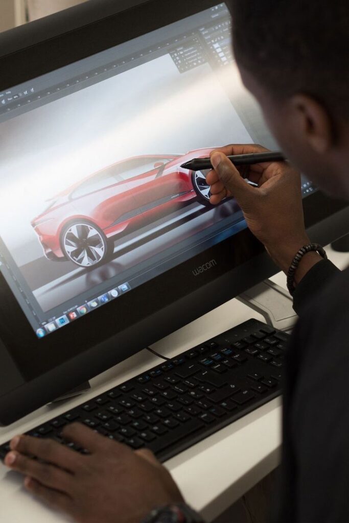 Designer creating a sleek red car concept on a digital tablet, showcasing automotive design software.