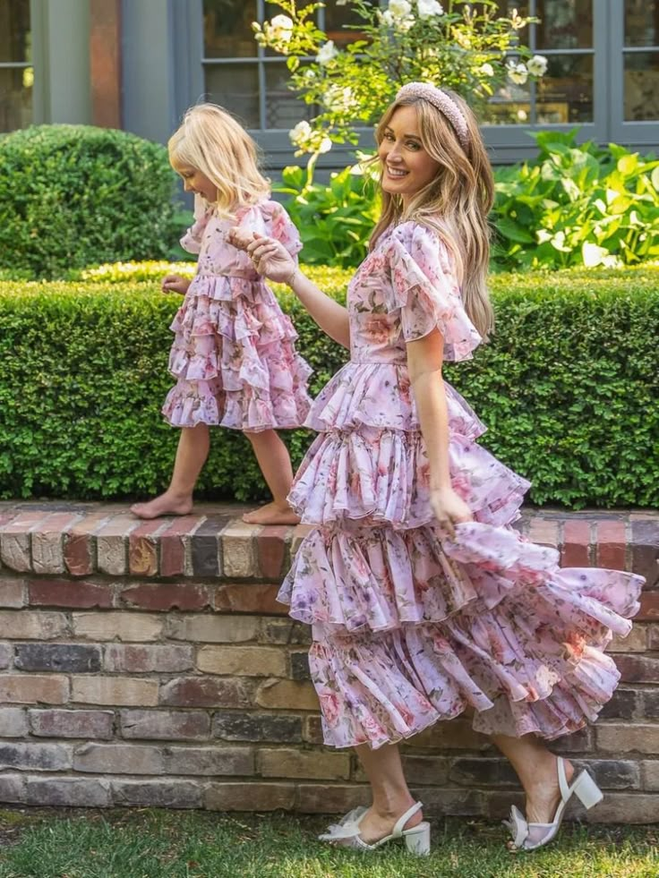 Mother and daughter in matching floral dresses enjoying a garden walk.