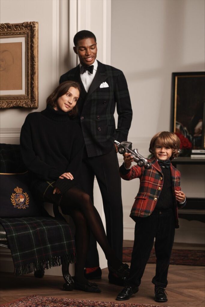 Family dressed in elegant, plaid outfits; young boy smiling with toy car.