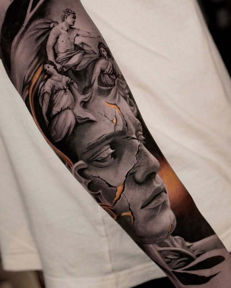 Detailed grayscale tattoo on arm featuring classical figures and a cracked, intense face.