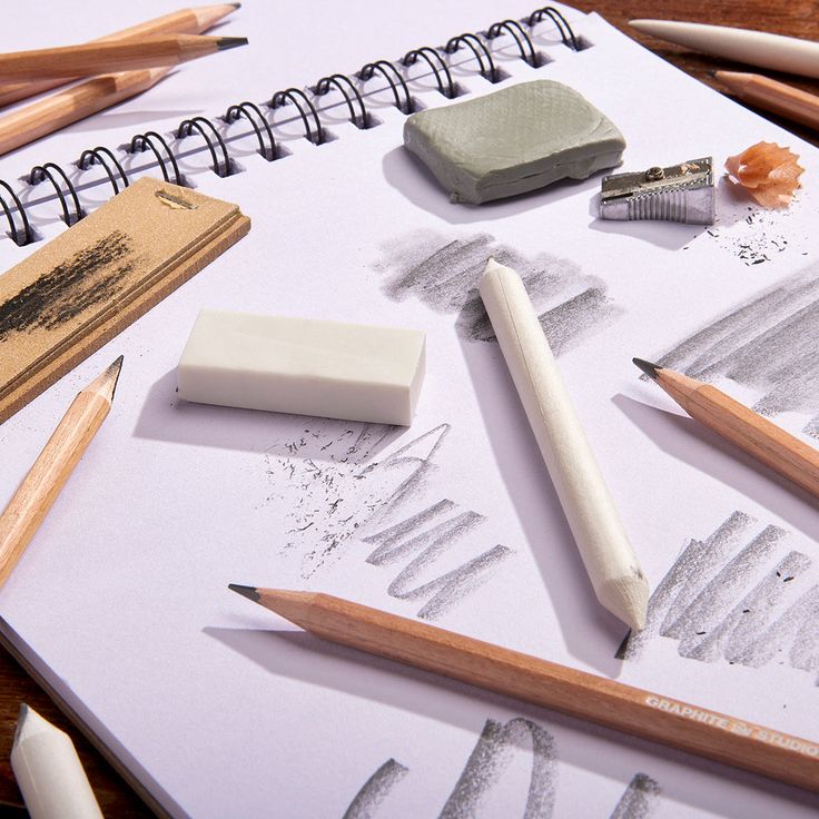 Art sketching tools on a notebook, featuring pencils, erasers, sharpener, and smudges. Ideal for drawing inspiration.