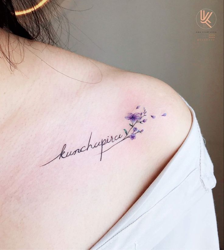 Delicate shoulder tattoo with purple flowers and cursive script, featuring the word kunchupira.