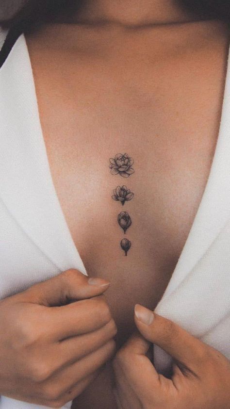 Elegant floral chest tattoo in black ink on a woman wearing a white robe, showcasing intricate floral design.