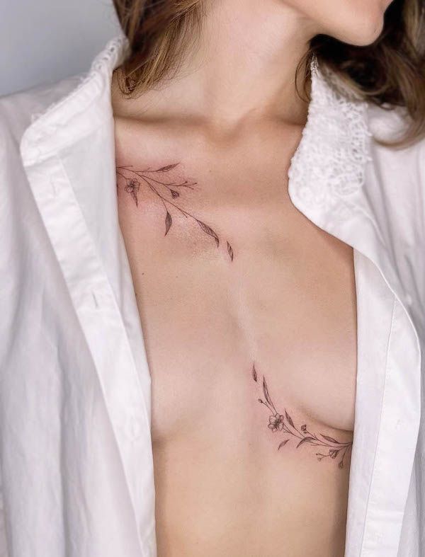 Minimalist floral collarbone tattoo on a person wearing a white shirt, displaying elegant line art and leaf design.