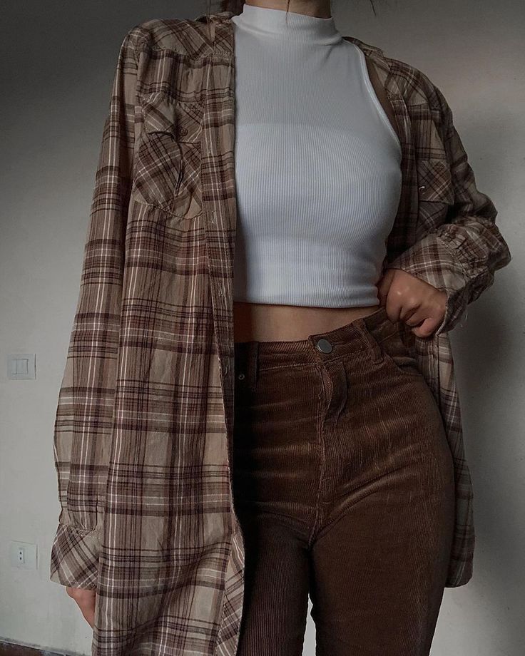 Casual outfit with plaid shirt, white crop top, and brown corduroy pants for a trendy fall look.