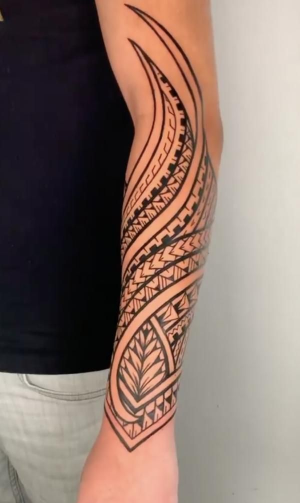 Detailed tribal tattoo design on a forearm, showcasing intricate patterns and bold lines.