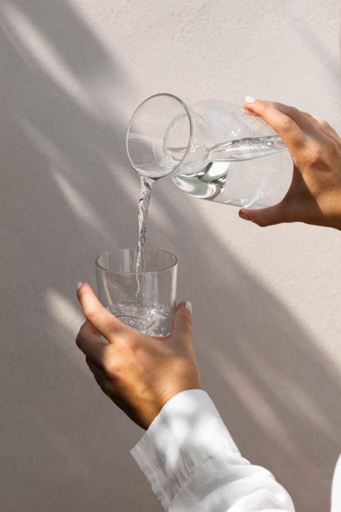 Pouring water from a glass jug into a glass, highlighting hydration and freshness.