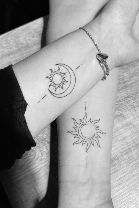 Matching sun and moon tattoos on arms, symbolizing balance and harmony, featuring a line design on a wooden surface.