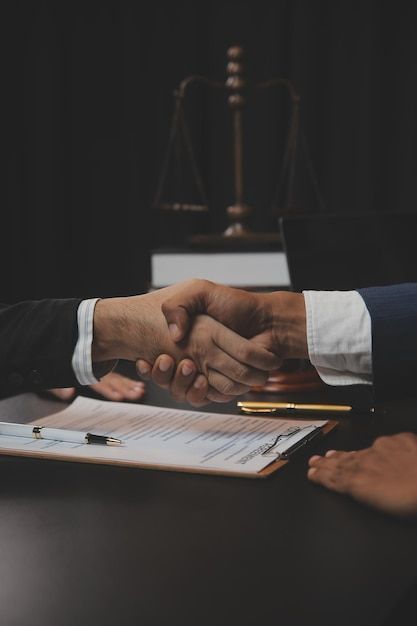 Handshake over contract with scales of justice in background, symbolizing partnership and legal agreement.