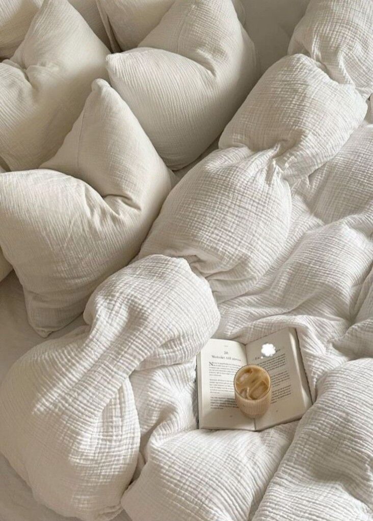 Cozy white bedding with a book and coffee, perfect for relaxation and comfort.