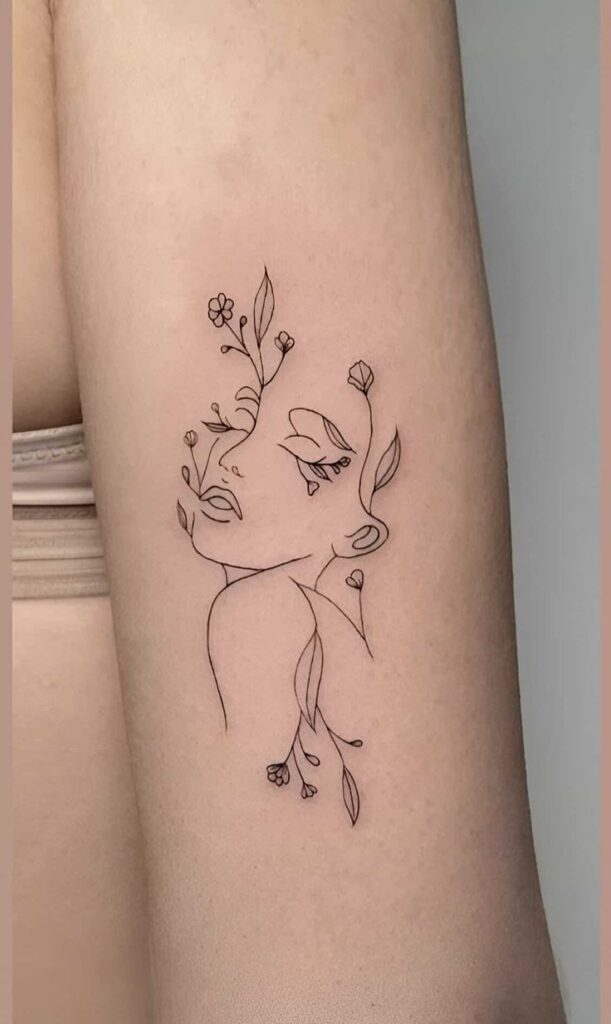 Minimalist floral face line tattoo on arm, blending nature and art beautifully.