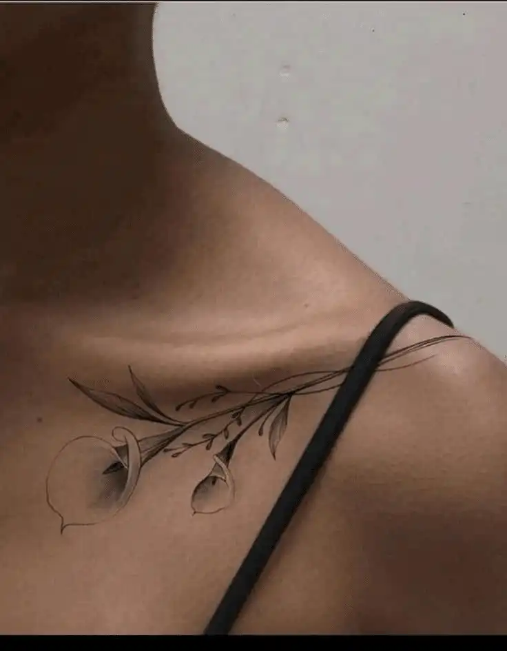 image Elegant shoulder tattoo of a delicate floral design with leaves, showcasing artistic and minimalist ink work on skin. | Sky Rye Design Elegant shoulder tattoo of a delicate floral design with leaves, showcasing artistic and minimalist ink work on skin.