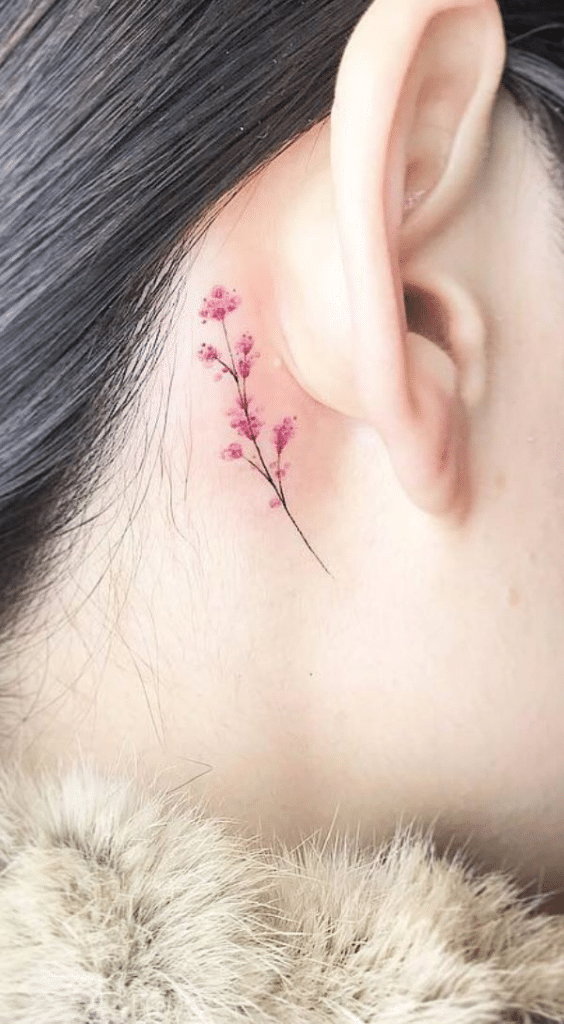 image Delicate pink flower tattoo behind ear, showcasing intricate floral design. Perfect inspiration for subtle, elegant body art ideas. | Sky Rye Design Delicate pink flower tattoo behind ear, showcasing intricate floral design. Perfect inspiration for subtle, elegant body art ideas.