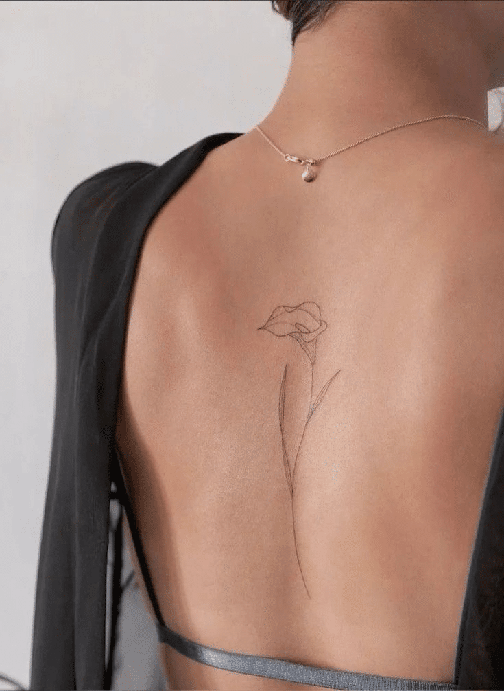 image Minimalist flower tattoo on a woman's back, elegantly highlighting her shoulder blade with a delicate black ink design. | Sky Rye Design Minimalist flower tattoo on a woman's back, elegantly highlighting her shoulder blade with a delicate black ink design.