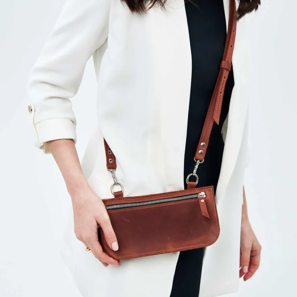 Woman wearing white blazer with brown leather crossbody purse. Fashionable and elegant accessory.