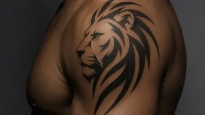 Black ink tribal lion shoulder tattoo on muscular male upper arm and torso, bold linework and flowing mane design