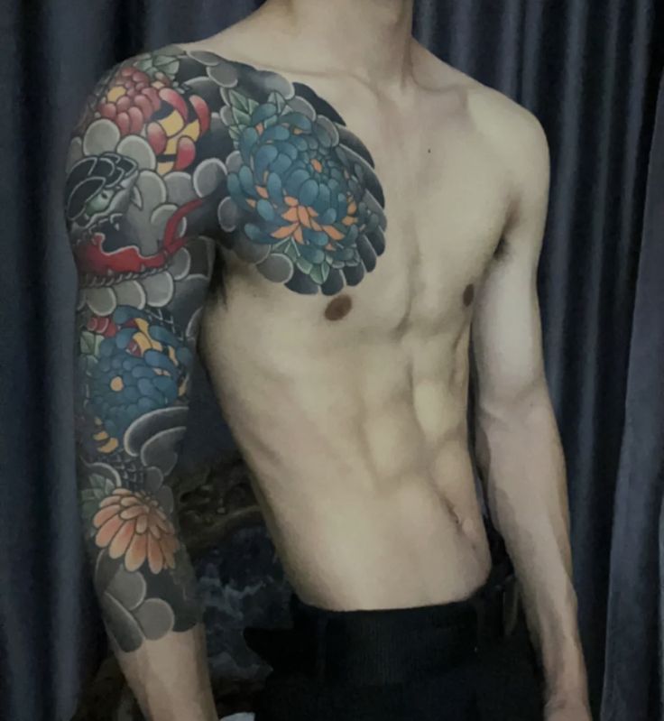 Man with intricate floral and dragon sleeve tattoo, showcasing detailed body art on arm and chest.