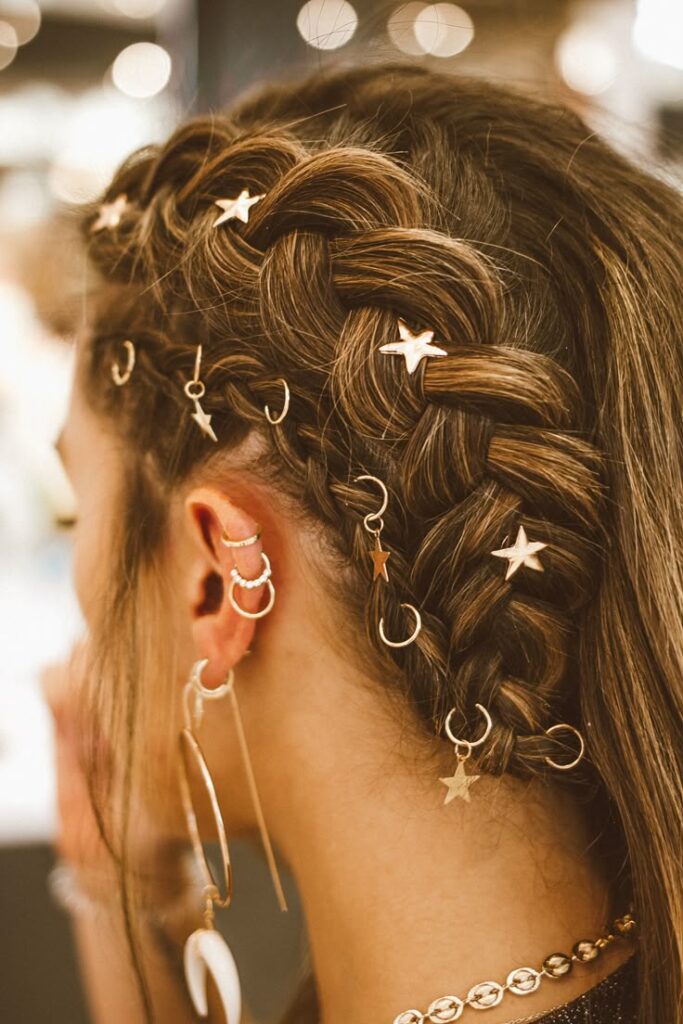 Intricate braided hairstyle adorned with star charms and hoop earrings, showcasing creative hair accessories.