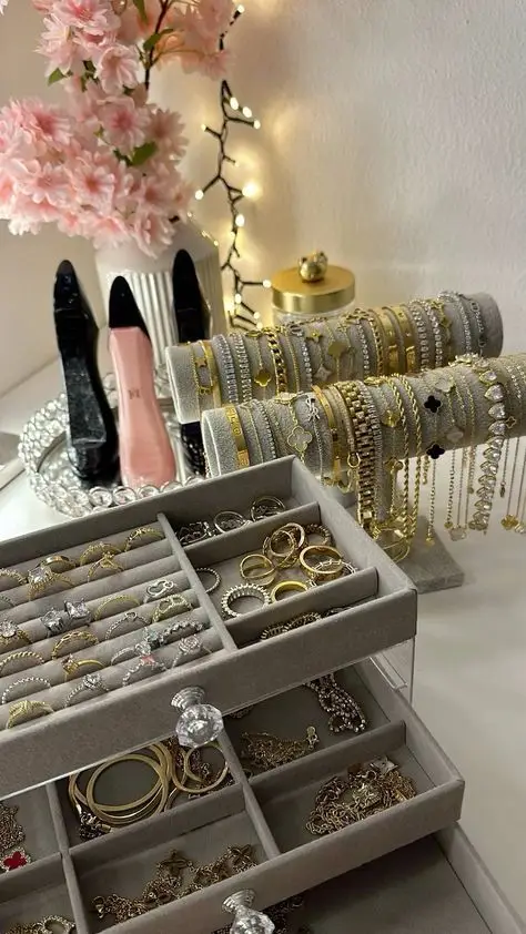 Elegant jewelry display with bracelets, rings, and necklaces; pink flowers and fairy lights in the background.
