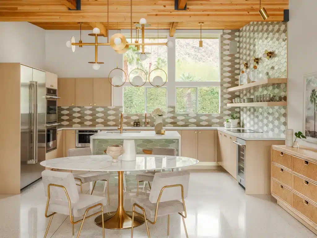 Modern kitchen with wooden cabinets, gold accents, marble table, and geometric backsplash. Bright, airy, and stylish design.