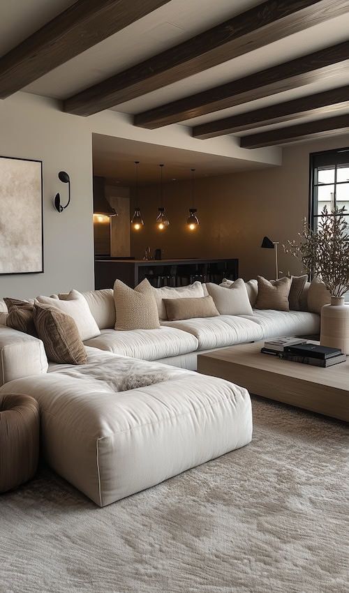 Modern living room with white sectional sofa, wooden beams, and soft lighting for a cozy, inviting atmosphere.